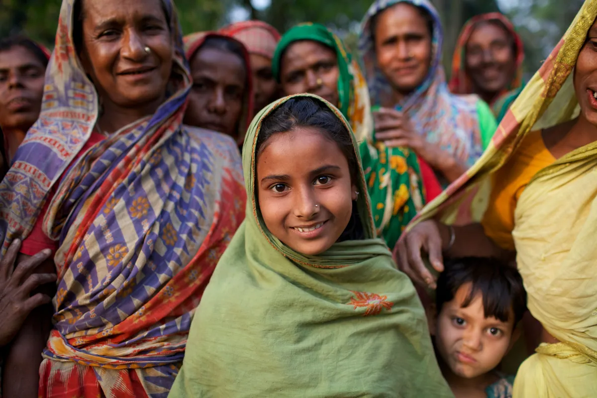 A girl sitting among a group of elder women, listening.