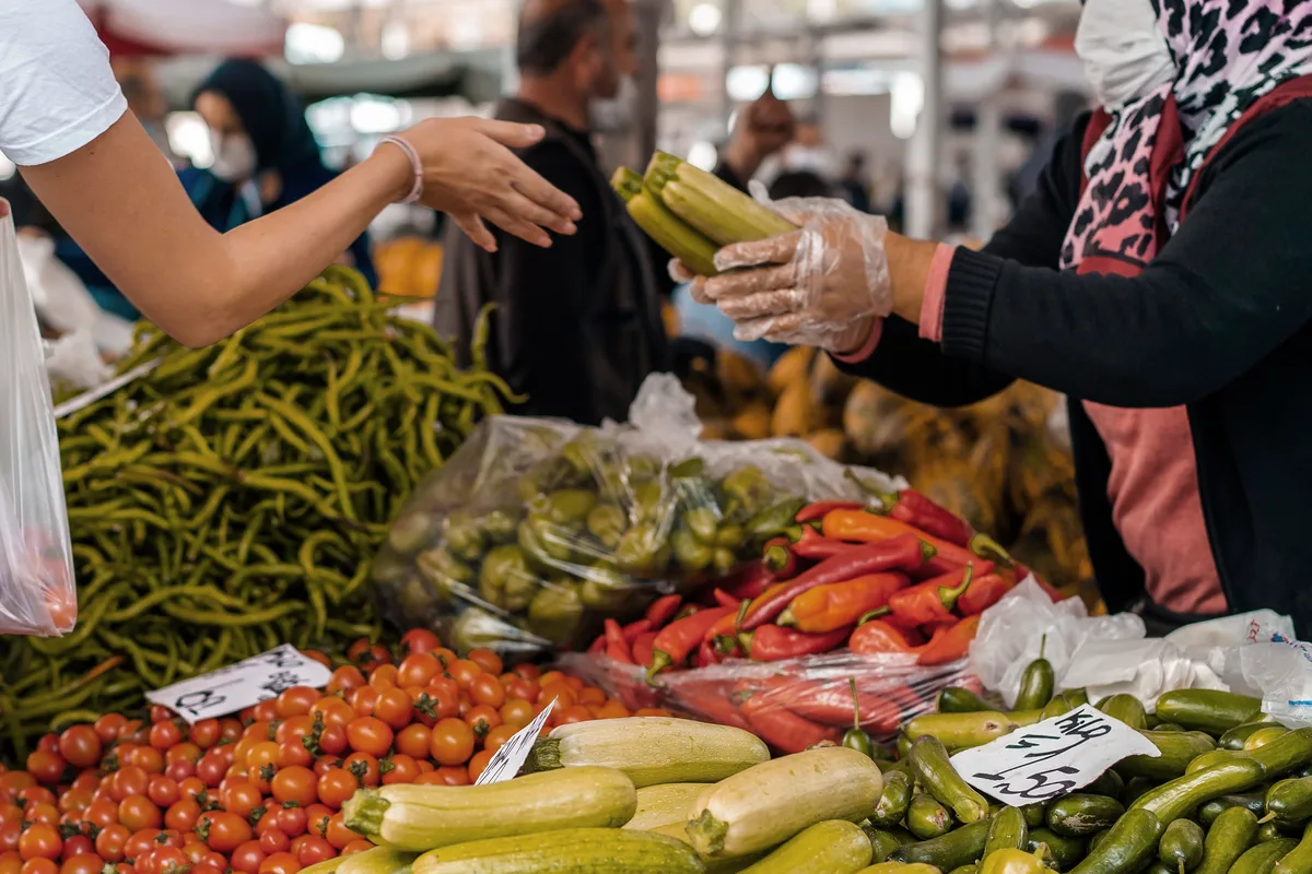 A customer and market vendor exchanging fresh produce
