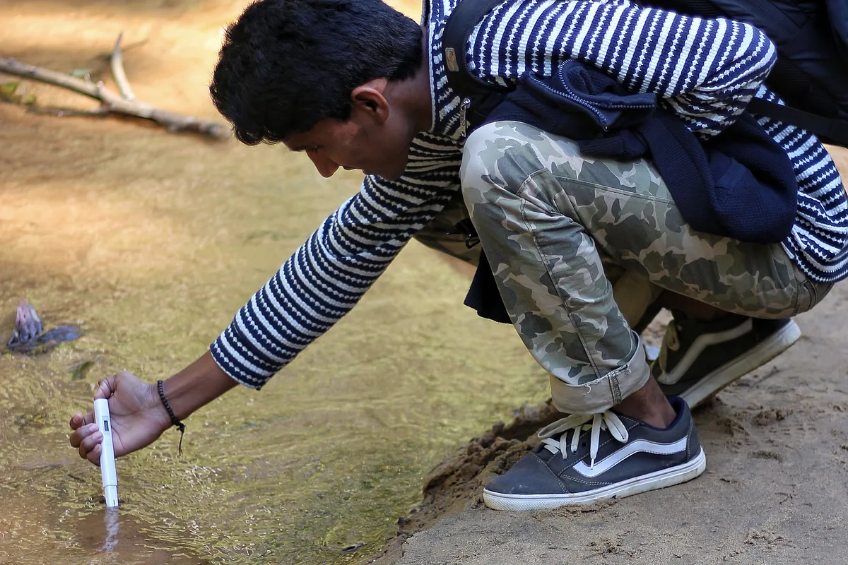 A field researcher measuring water quality in a stream