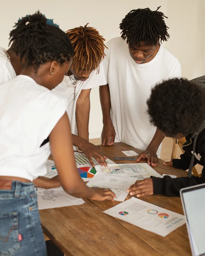 Four people examining maps and charts together around a table.